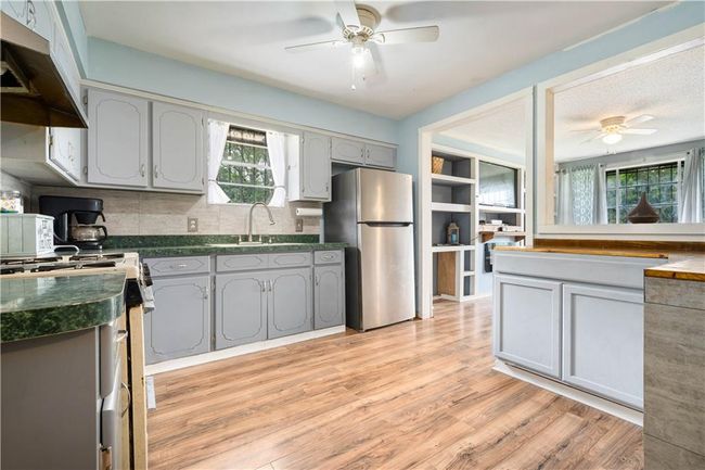 Kitchen with freestanding refrigerator, dark countertops, white range with gas cooktop, under cabinet range hood, and a ceiling fan | Image 8