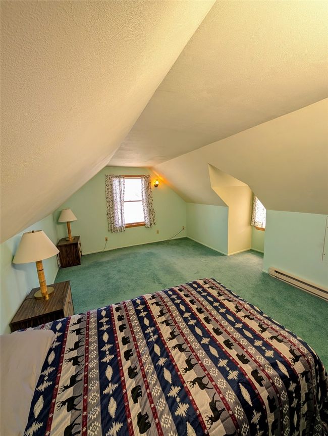 Unfurnished bedroom featuring lofted ceiling, carpet floors, a textured ceiling, and a baseboard heating unit | Image 13