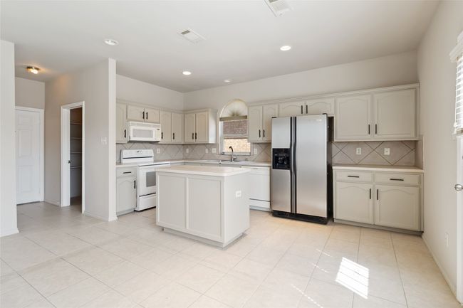 Kitchen featuring visible vents, white appliances, a kitchen island, and light countertops | Image 22