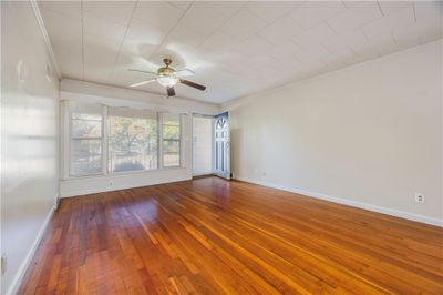 Empty room featuring crown molding, hardwood / wood-style floors, and ceiling fan | Image 2