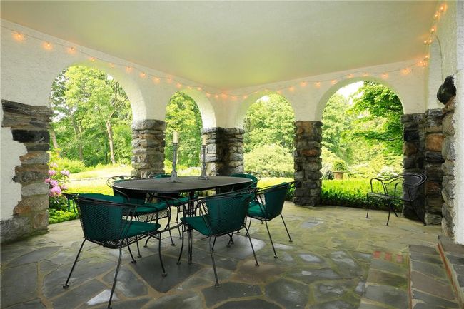 Covered stone, stucco and slate loggia accessed from the formal dining room and formal living room | Image 5