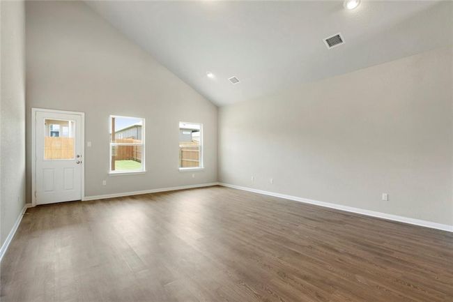 Empty room with high vaulted ceiling, dark wood-style floors, and baseboards | Image 9