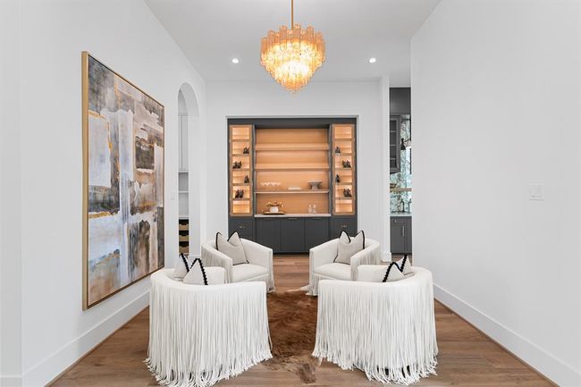 This sophisticated lounge features custom built-in cabinetry with illuminated shelving, creating a warm and inviting space perfect for displaying décor or entertaining in style. | Image 8