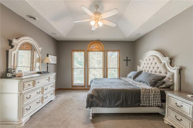 Bedroom with light colored carpet, lofted ceiling, visible vents, and multiple windows | Image 34