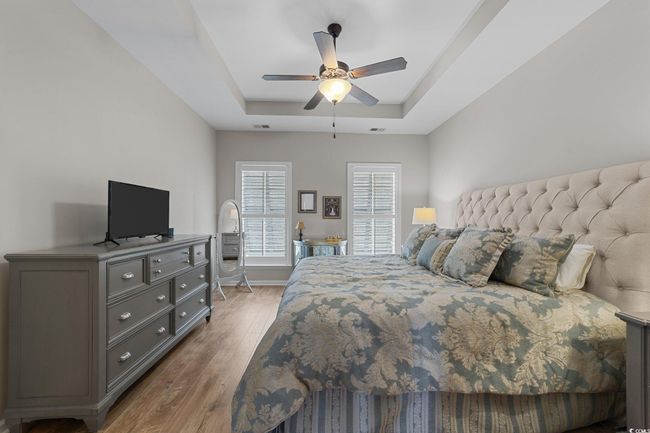 Bedroom featuring a tray ceiling, wood finished floors, ceiling fan, and baseboards | Image 14