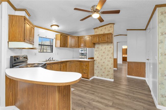 Kitchen with black electric range, extractor fan, lofted ceiling, a peninsula, and ceiling fan | Image 7