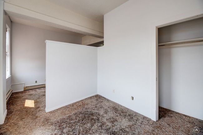 An Unfurnished future bedroom area with a closet, carpet flooring, a baseboard heating unit, and baseboard heating | Image 10