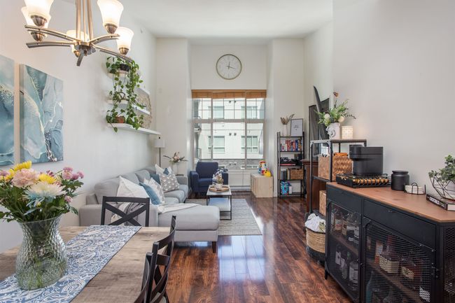 Living area with a chandelier, wood finished floors, and a high ceiling | Image 7