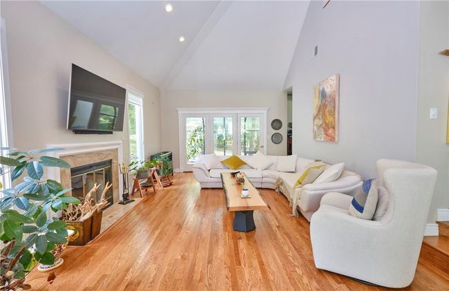Living room featuring high vaulted ceiling, a fireplace, and light hardwood / wood-style flooring | Image 13