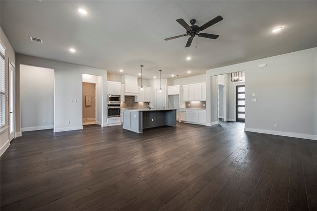Kitchen featuring a ceiling fan, visible vents, stainless steel appliances, open floor plan, and dark wood-style floors | Image 8