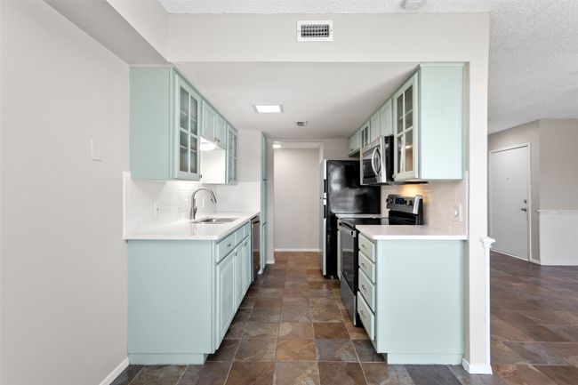 Kitchen featuring a sink, appliances with stainless steel finishes, stone finish floor, and tasteful backsplash | Image 17