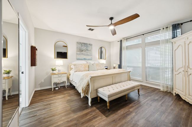Spacious primary bedroom featuring dark wood-style floors and ceiling fan | Image 16