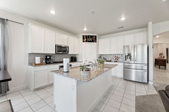 Kitchen featuring backsplash, light tile flooring, arched walkways, and appliances with stainless steel finishes | Image 15