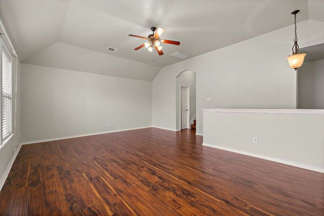 Spacious Loft room featuring vaulted ceiling, a ceiling fan, wood finished floors, and windows | Image 25