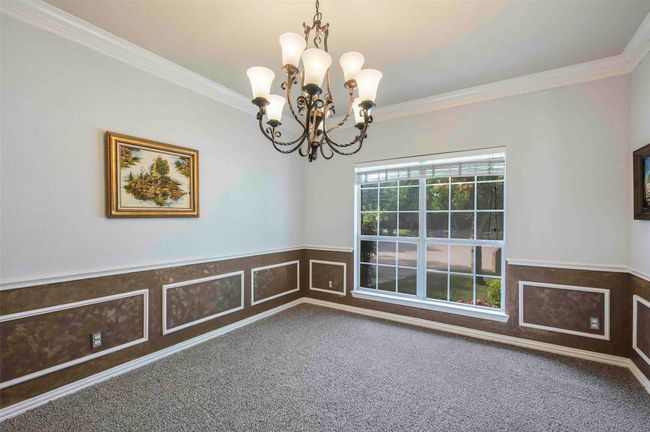 Empty room featuring ornamental molding, a wainscoted wall, carpet flooring, and a chandelier | Image 5