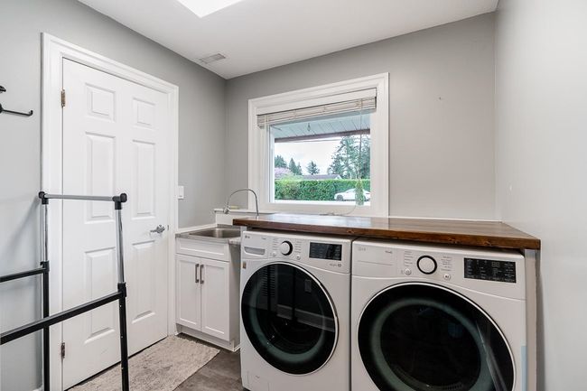 Washroom with washing machine and dryer, visible vents, cabinet space, and a sink | Image 24