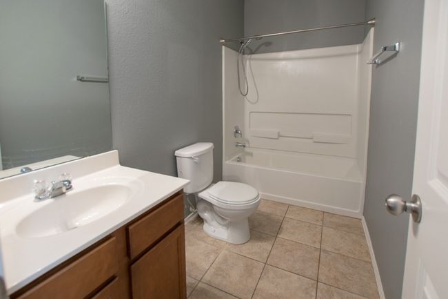 Bathroom with vanity, shower / bath combination, toilet, tile patterned flooring, and baseboards | Image 31