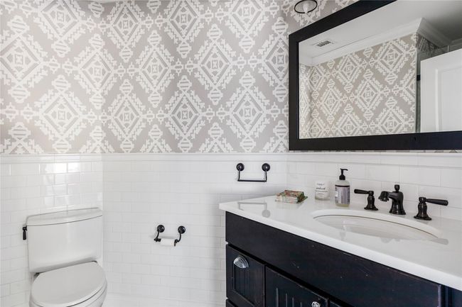 Bathroom with toilet, visible vents, wallpapered walls, and tile walls | Image 11