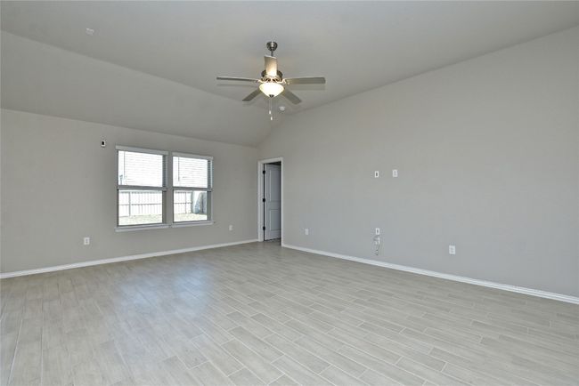 Empty room with vaulted ceiling, light wood-style flooring, baseboards, and ceiling fan | Image 7