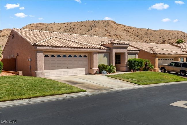 View of front facade featuring concrete driveway, a mountain view, a garage, stucco siding, and a front lawn | Image 51