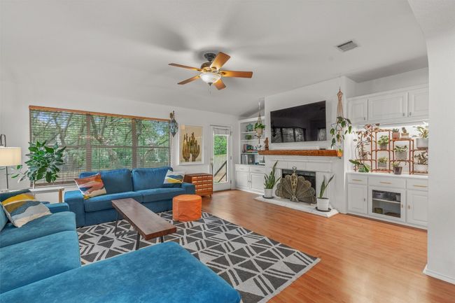 Living room with a fireplace with raised hearth, a ceiling fan, and light wood-style flooring | Image 16