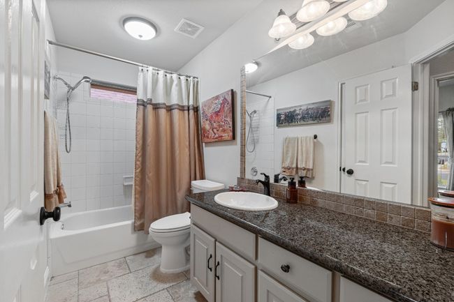 Bathroom featuring shower / tub combo, vanity, and stone tile flooring | Image 25