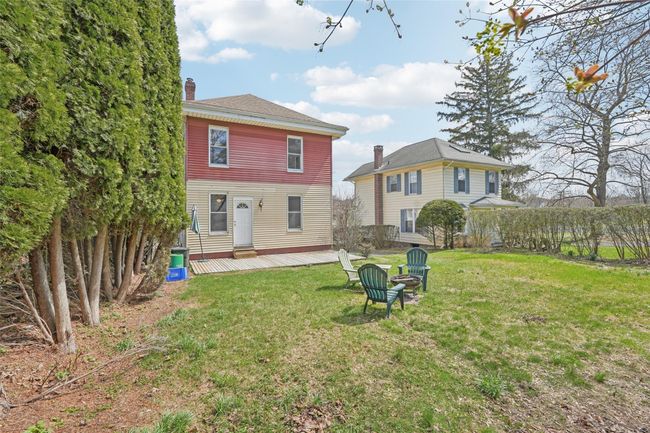 Rear view of property featuring a yard, a deck, and a chimney | Image 35