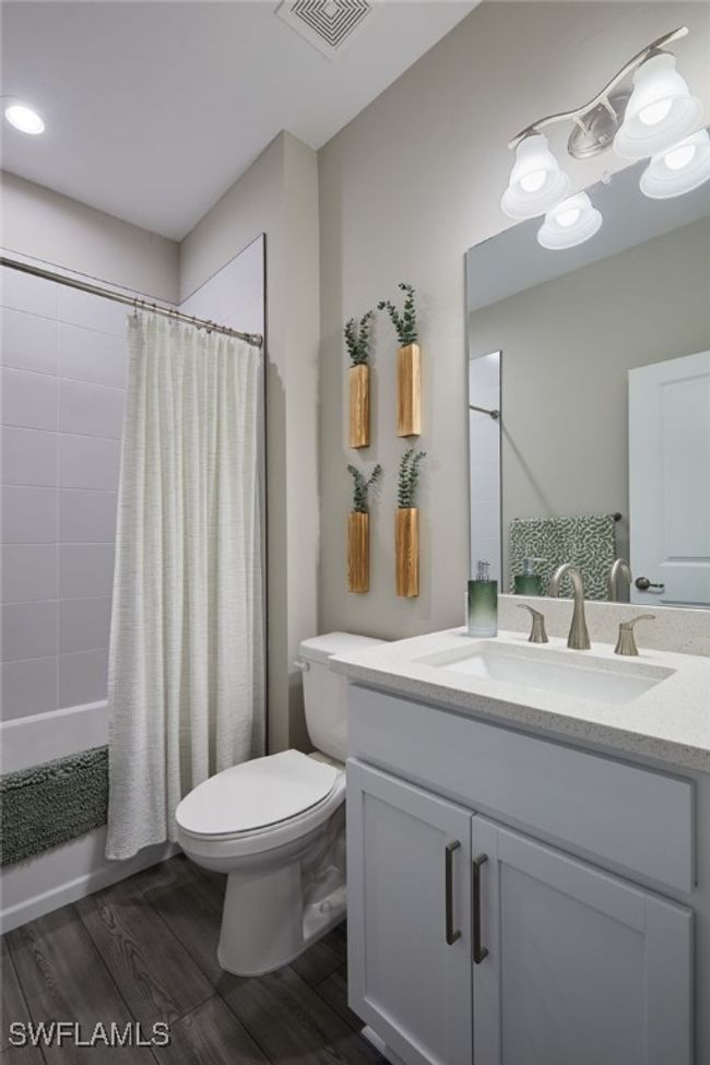 Bathroom featuring toilet, wood finished floors, vanity, visible vents, and shower / tub combo with curtain | Image 13