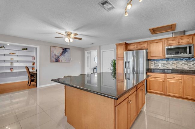 Kitchen featuring baseboards, ceiling fan, dark stone counters, tasteful backsplash, and appliances with stainless steel finishes | Image 24