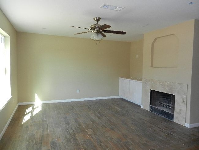 Unfurnished living room with ceiling fan, wood finished floors, a high end fireplace, and healthy amount of natural light | Image 7