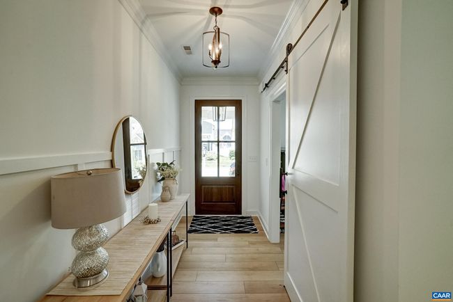 Modern lighting, and upgraded trim detailing like wainscoting in the foyer and sliding barn door. | Image 6