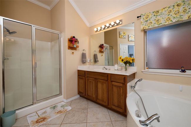 Bathroom featuring a garden tub, ornamental molding, vanity, and a stall shower | Image 31