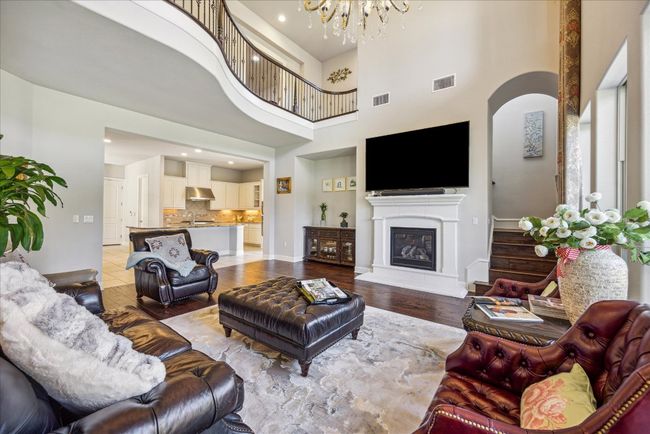 Living area with light wood-style flooring, visible vents, an inviting chandelier, and a glass covered fireplace | Image 8