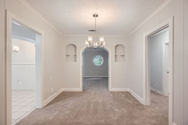 Spare room featuring arched walkways, an inviting chandelier, a textured ceiling, and ornamental molding | Image 10