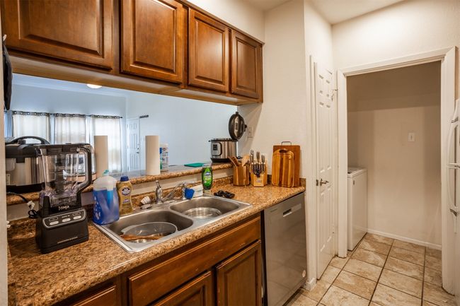 Kitchen with stainless steel dishwasher, light tile patterned floors, brown cabinets, and light countertops | Image 6