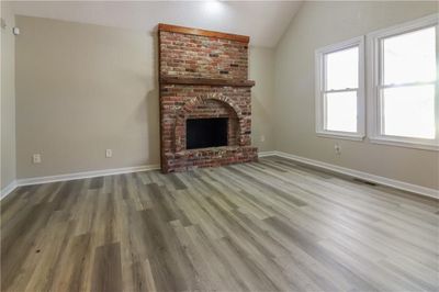 Unfurnished living room featuring a fireplace, hardwood / wood-style flooring, and vaulted ceiling | Image 3