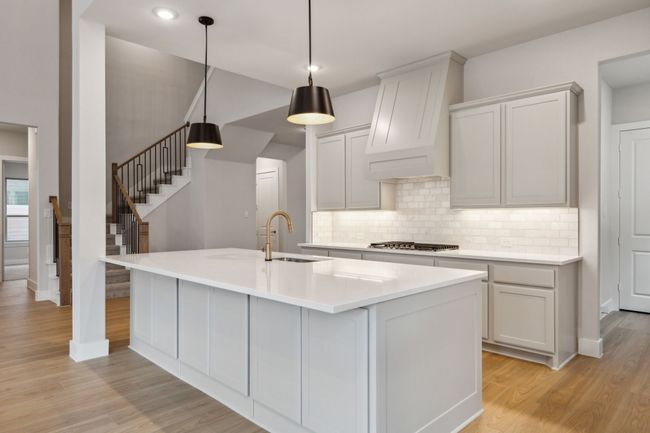 Kitchen with light wood-style flooring, backsplash, custom range hood, an island with sink, and recessed lighting | Image 11
