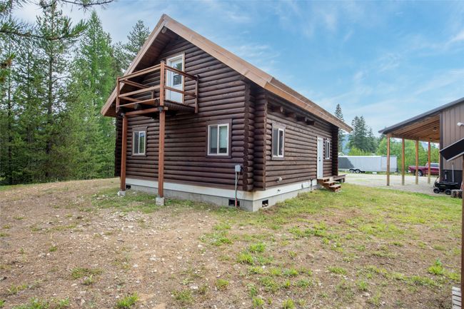 View of side of home featuring log exterior, entry steps, and a carport | Image 55