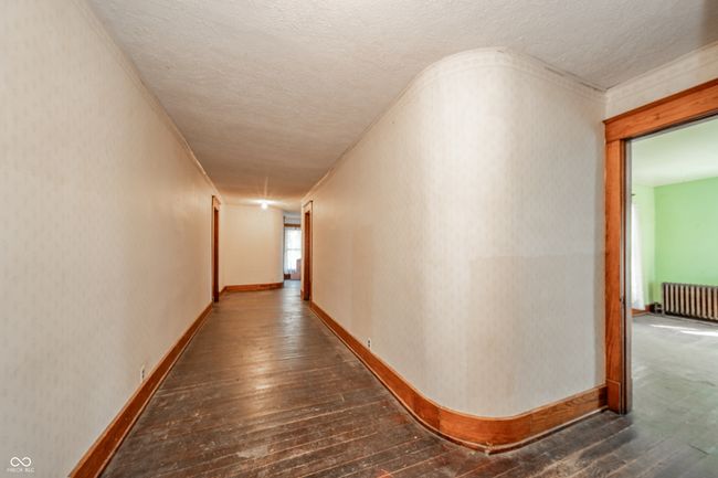 hallway with radiator heating unit, a textured ceiling, baseboards, and dark wood-style floors | Image 13