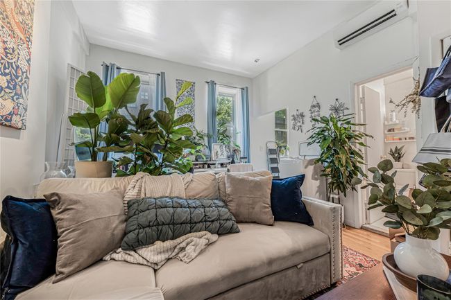 Living area with a wall unit AC and wood finished floors | Image 14