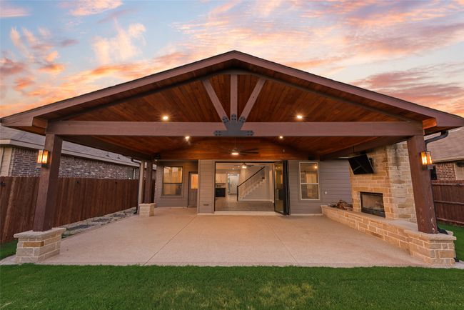 View of custom patio with an outdoor stone fireplace, and ceiling fan | Image 19