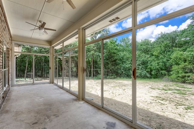 Unfurnished sunroom featuring ceiling fan, view of scattered trees, and healthy amount of natural light | Image 27