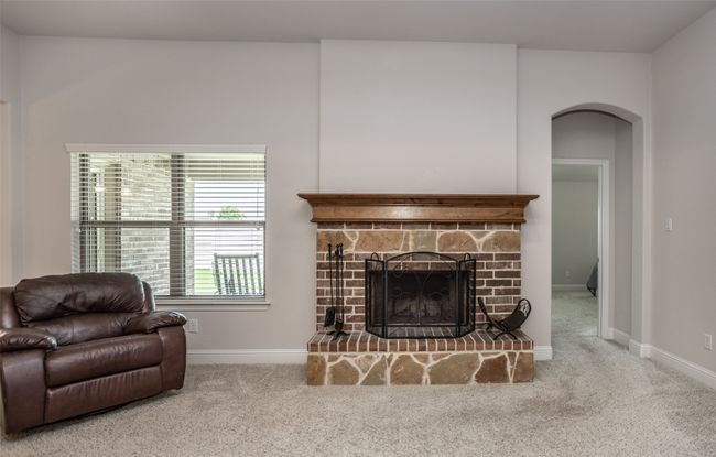 Carpeted living area featuring arched walkways and a stone fireplace | Image 9