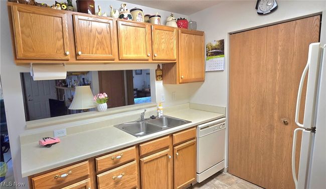 Kitchen with light countertops, a sink, brown cabinetry, and white appliances | Image 10