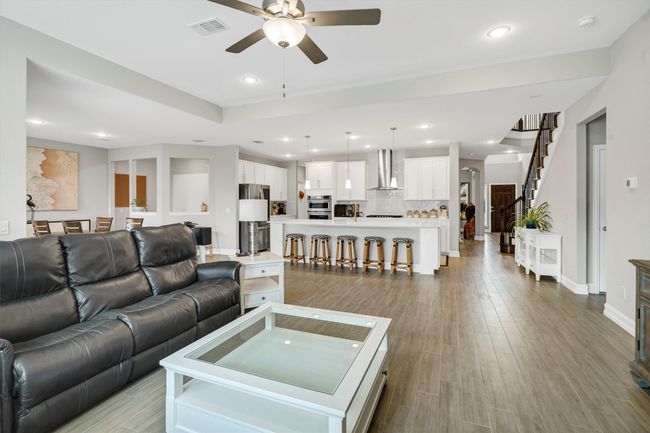 Living room features a ceiling fan, recessed lighting and wood-like tile floors. | Image 8