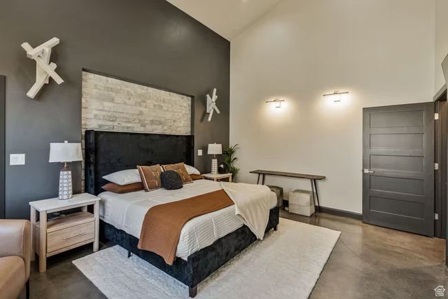 Bedroom featuring high vaulted ceiling, finished concrete flooring, and baseboards | Image 19