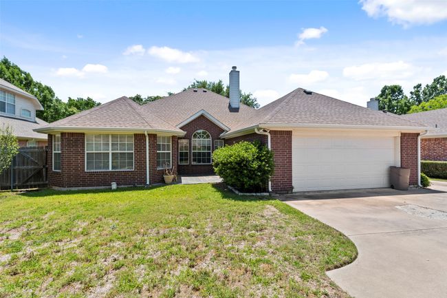 Ranch-style house with a chimney, brick siding, an attached garage, and concrete driveway | Image 38
