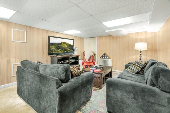 Carpeted living room with wooden walls and a drop ceiling | Image 27