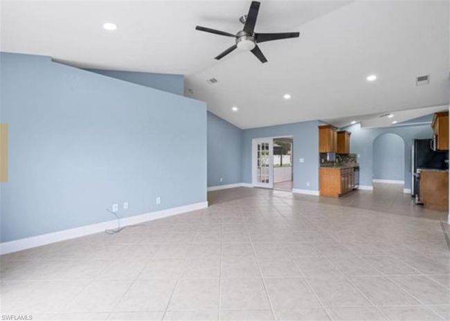Unfurnished living room with arched walkways, ceiling fan, recessed lighting, lofted ceiling, and light tile patterned flooring | Image 4