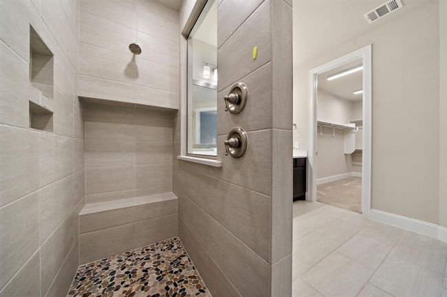 The walk-in shower features nitches for storage and a bench to sit down on. | Image 18